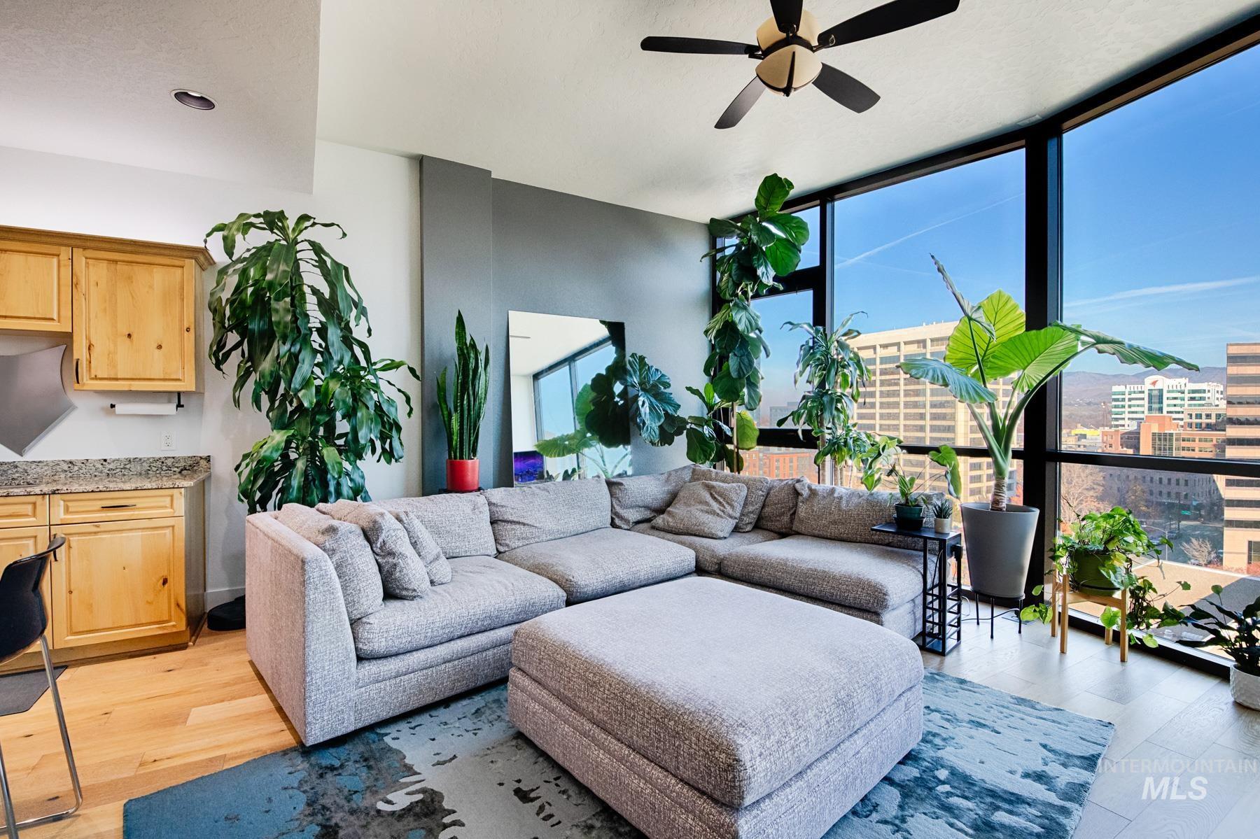 Living area with floor to ceiling windows, ceiling fan, and light wood-style floors