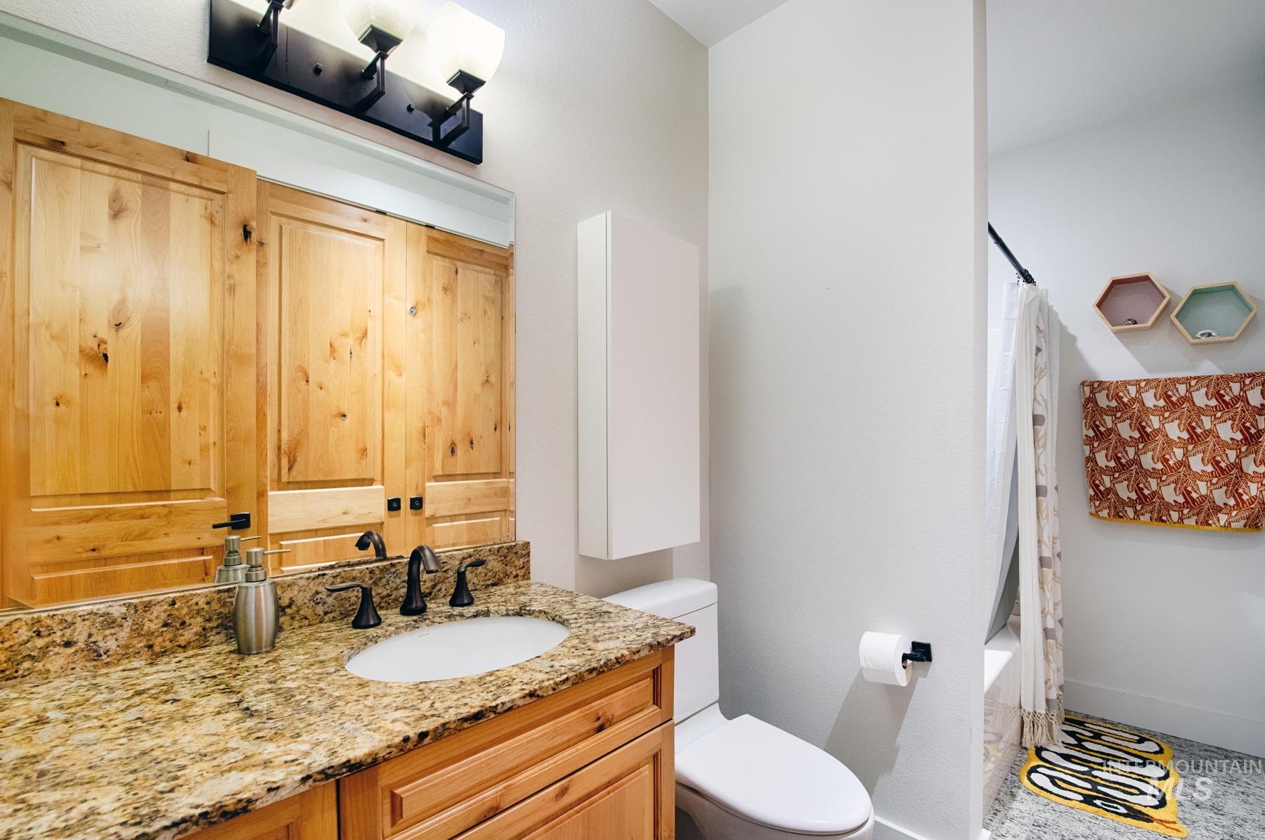 Bathroom featuring vanity and shower / bathtub combination with curtain