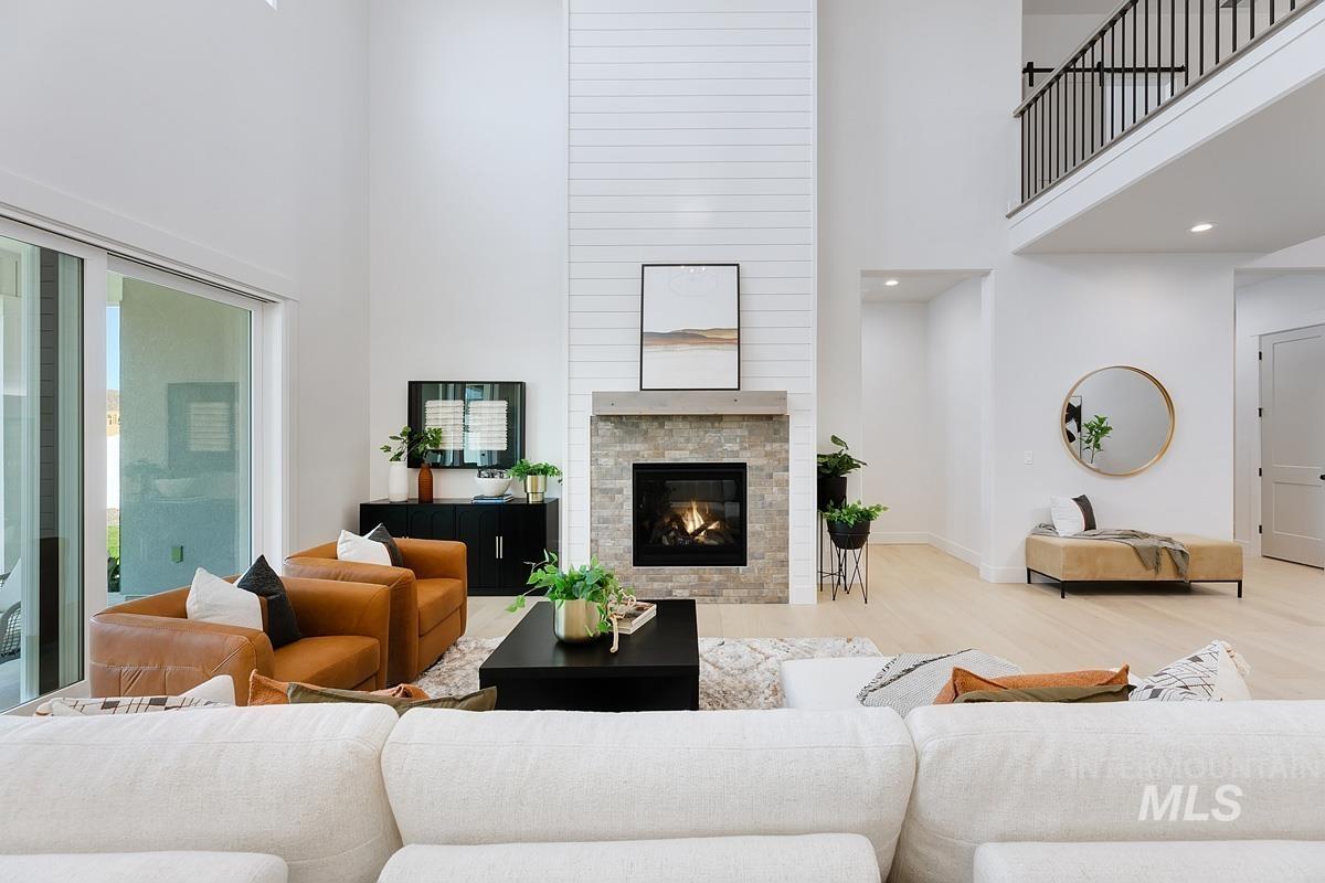 Living area featuring a high ceiling, wood finished floors, a glass covered fireplace, and recessed lighting