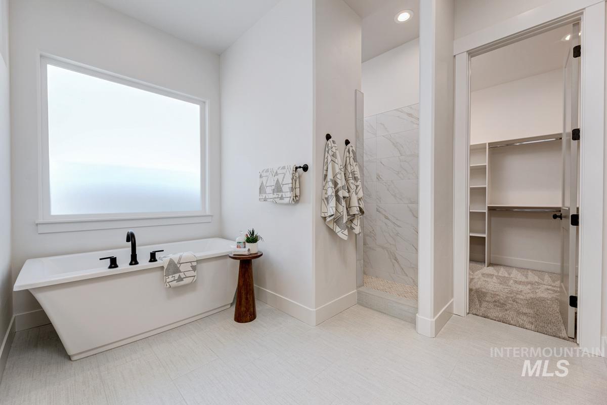 Bathroom with a freestanding tub, a marble finish shower, and a walk in closet