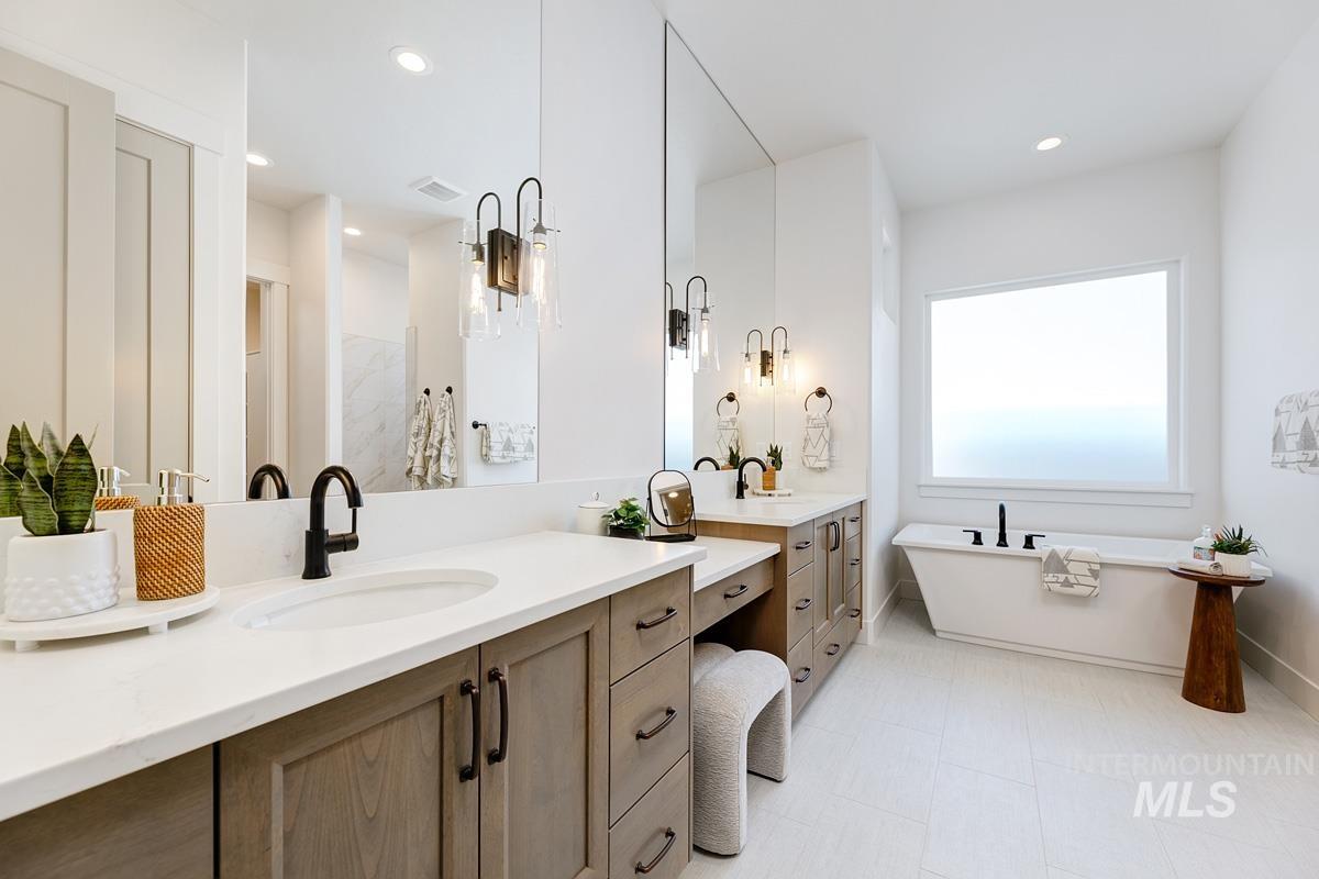 Full bath with double vanity, a freestanding tub, a walk in shower, and recessed lighting