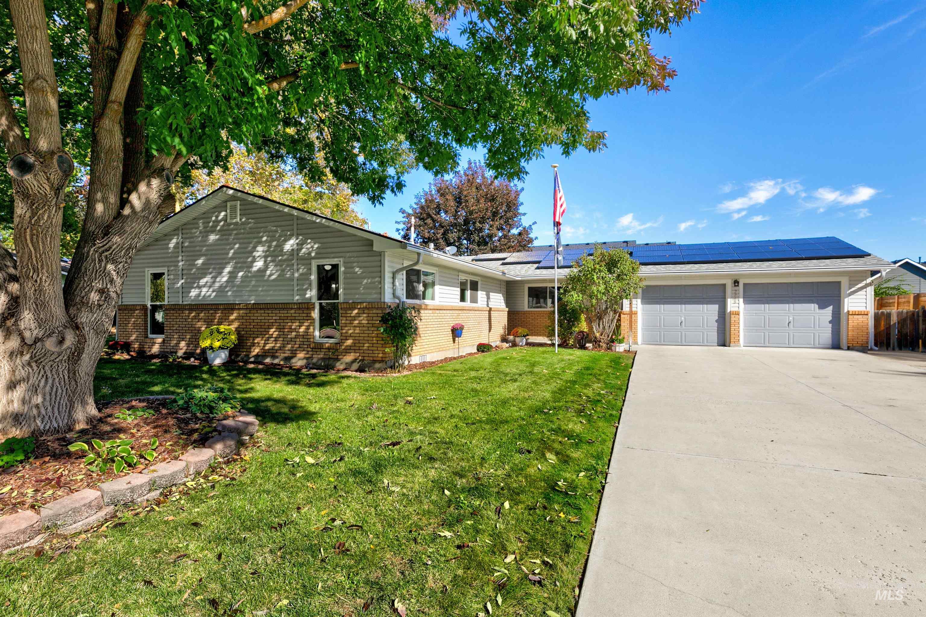 Ranch-style house featuring brick siding, solar panels, driveway, and an attached garage