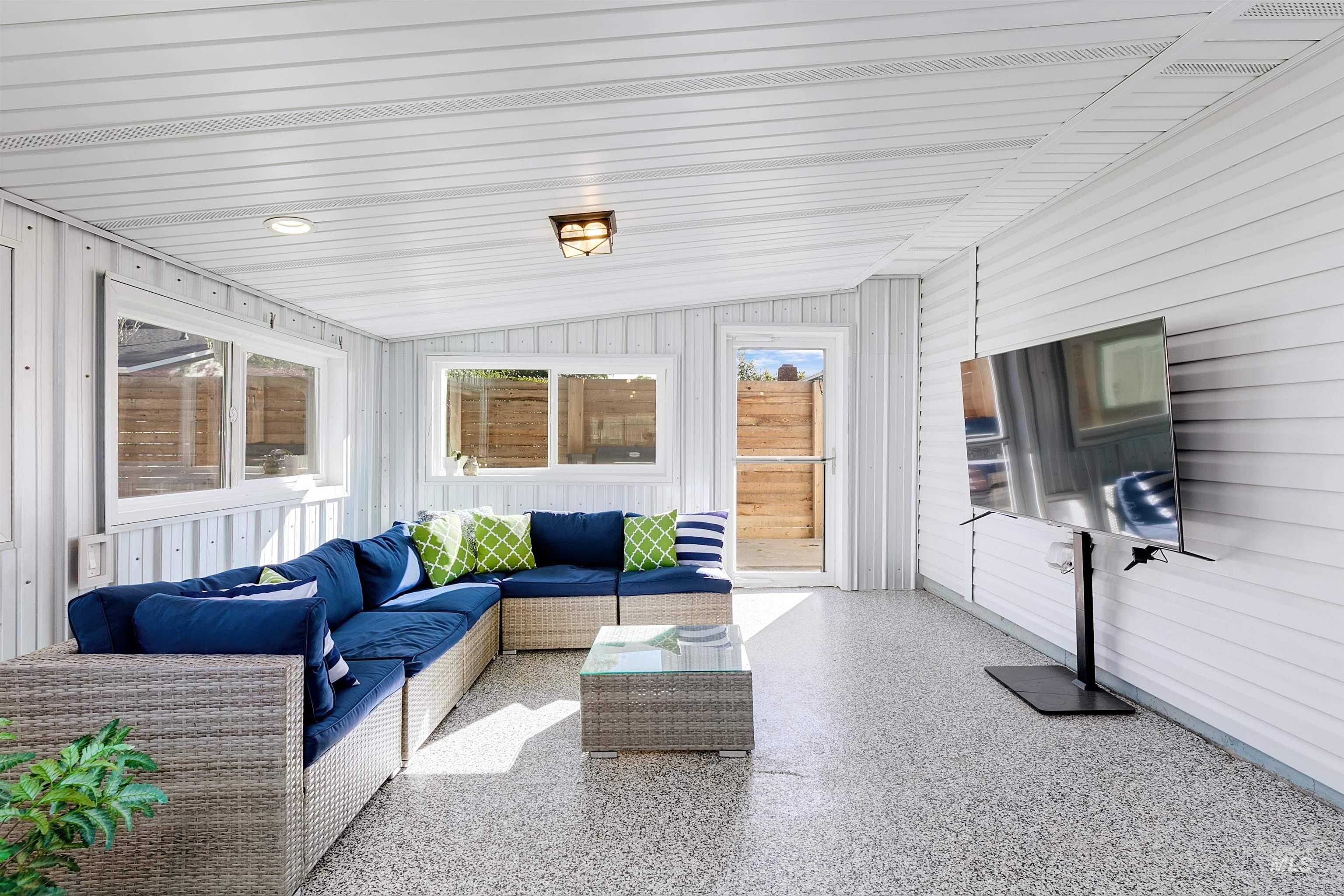 Sunroom / solarium with vaulted ceiling, lounge area and healthy amount of natural light.