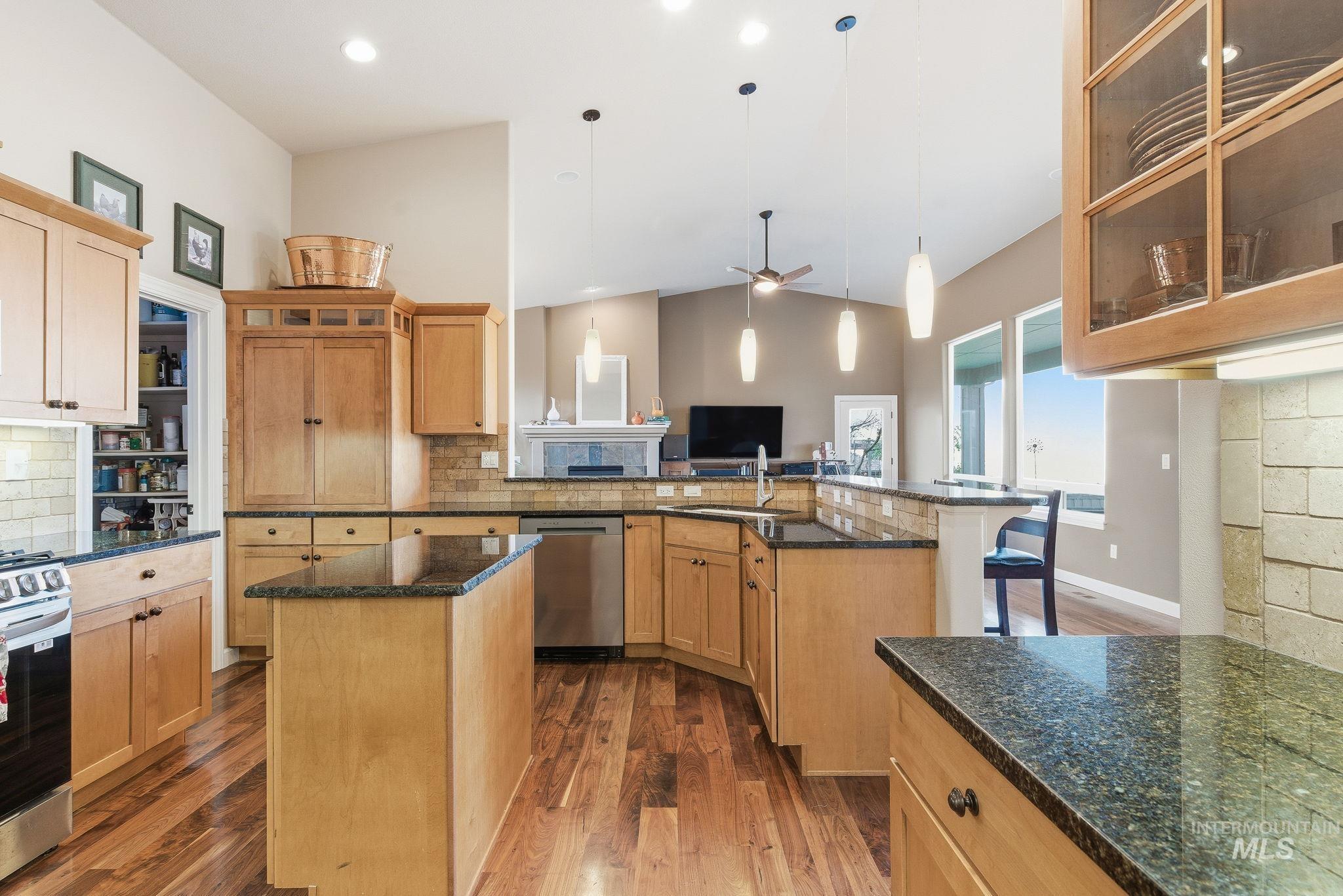 Kitchen featuring glass insert cabinets, pendant lighting, backsplash, a kitchen island, and dark stone countertops