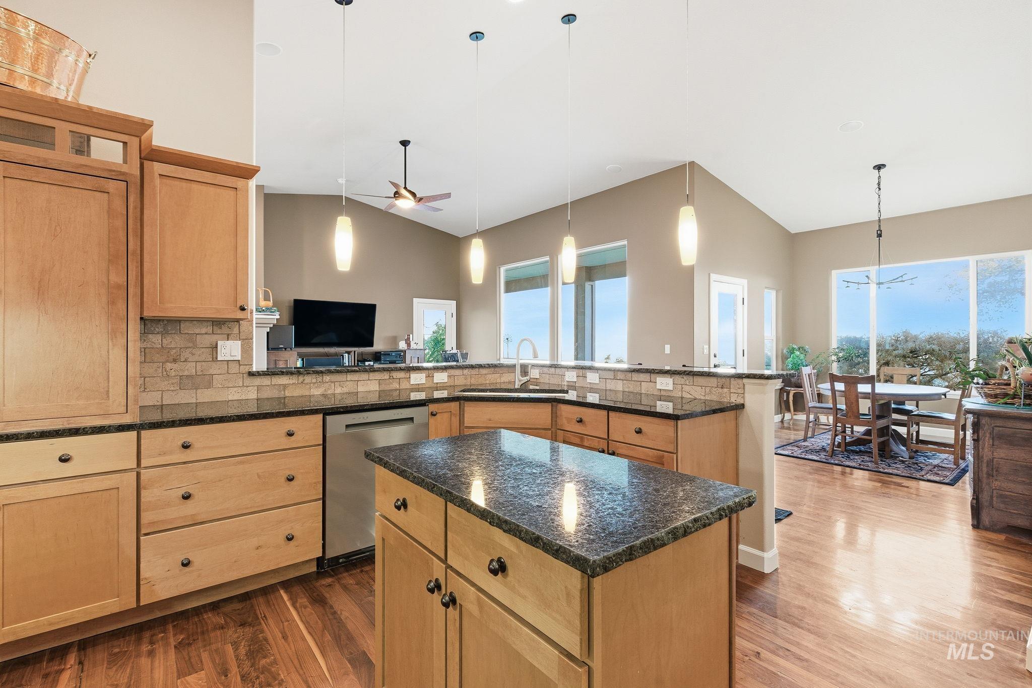 Kitchen with pendant lighting, backsplash, ceiling fan, and lofted ceiling