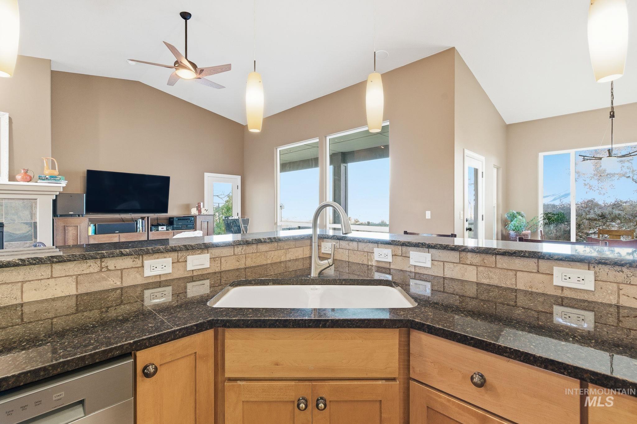Kitchen with pendant lighting, open floor plan, dishwasher, vaulted ceiling, and ceiling fan