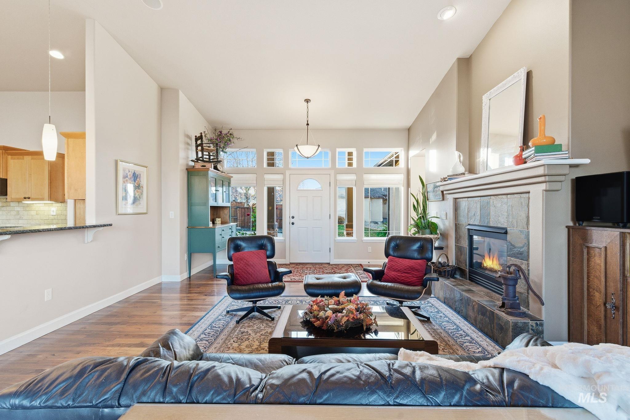 Living area featuring wood finished floors, a tiled fireplace, recessed lighting, and a high ceiling