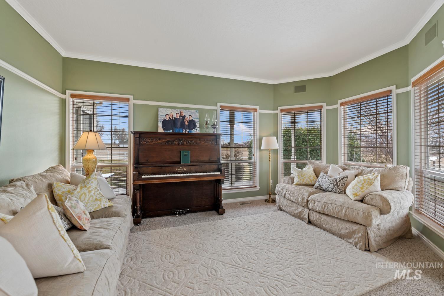 Carpeted living area with baseboards and crown molding