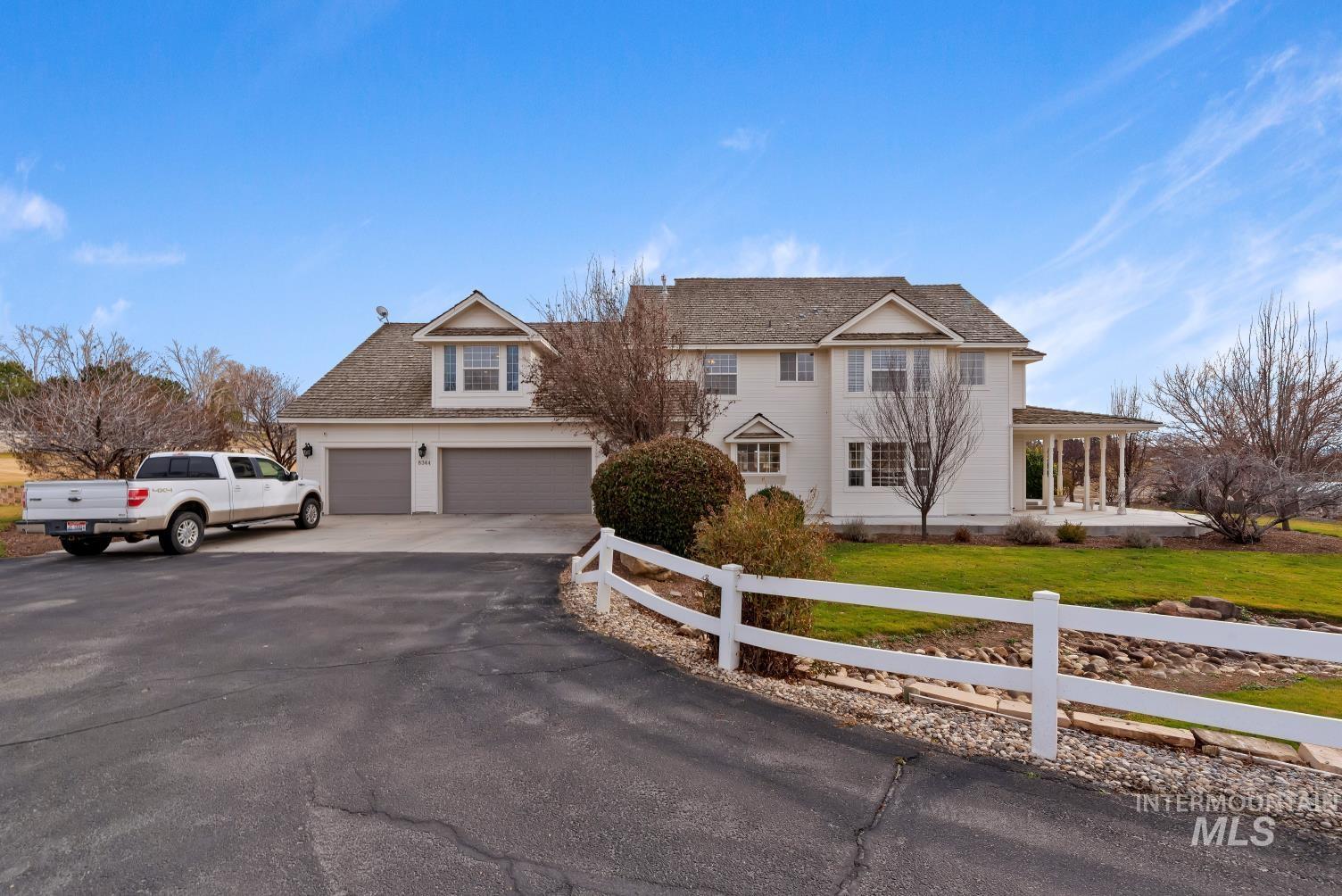 Traditional-style house with asphalt driveway, a garage, a fenced front yard, covered porch, and roof with shingles