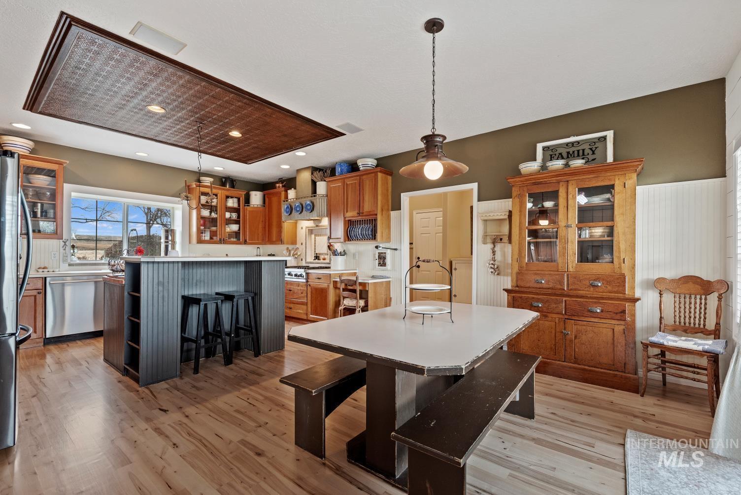 Kitchen with glass insert cabinets, a kitchen bar, light countertops, decorative light fixtures, and a kitchen island
