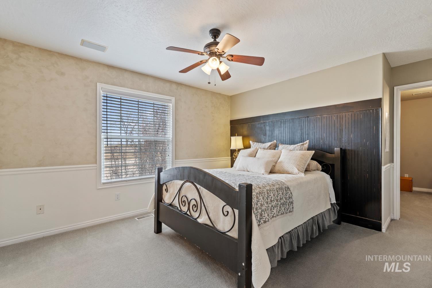 Carpeted bedroom with a ceiling fan and a textured ceiling