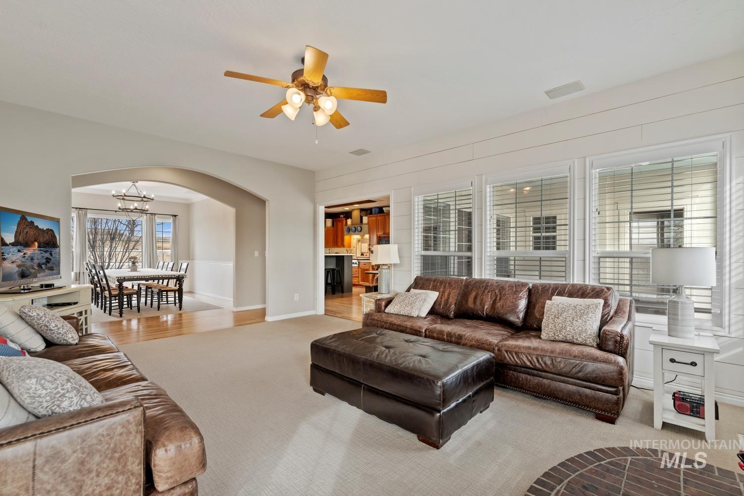 Living area with arched walkways, carpet floors, and ceiling fan
