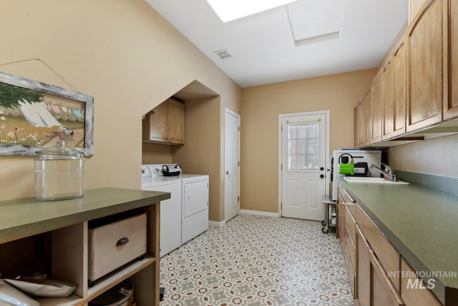 Laundry area with cabinet space, washer and clothes dryer, and light floors