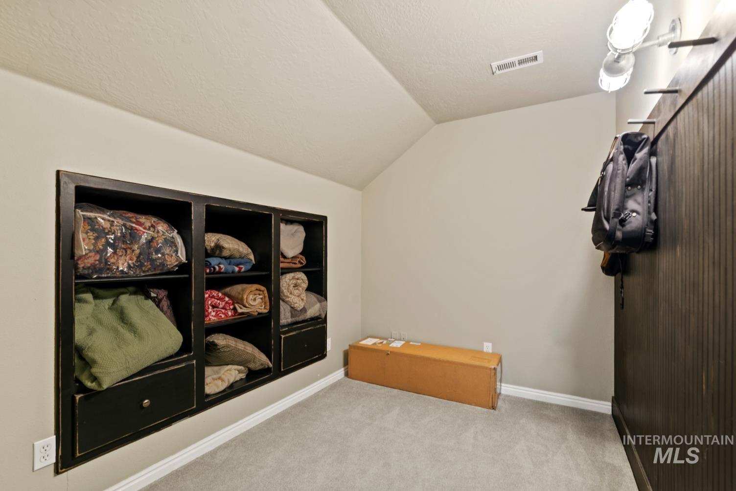Carpeted spare room with lofted ceiling and baseboards