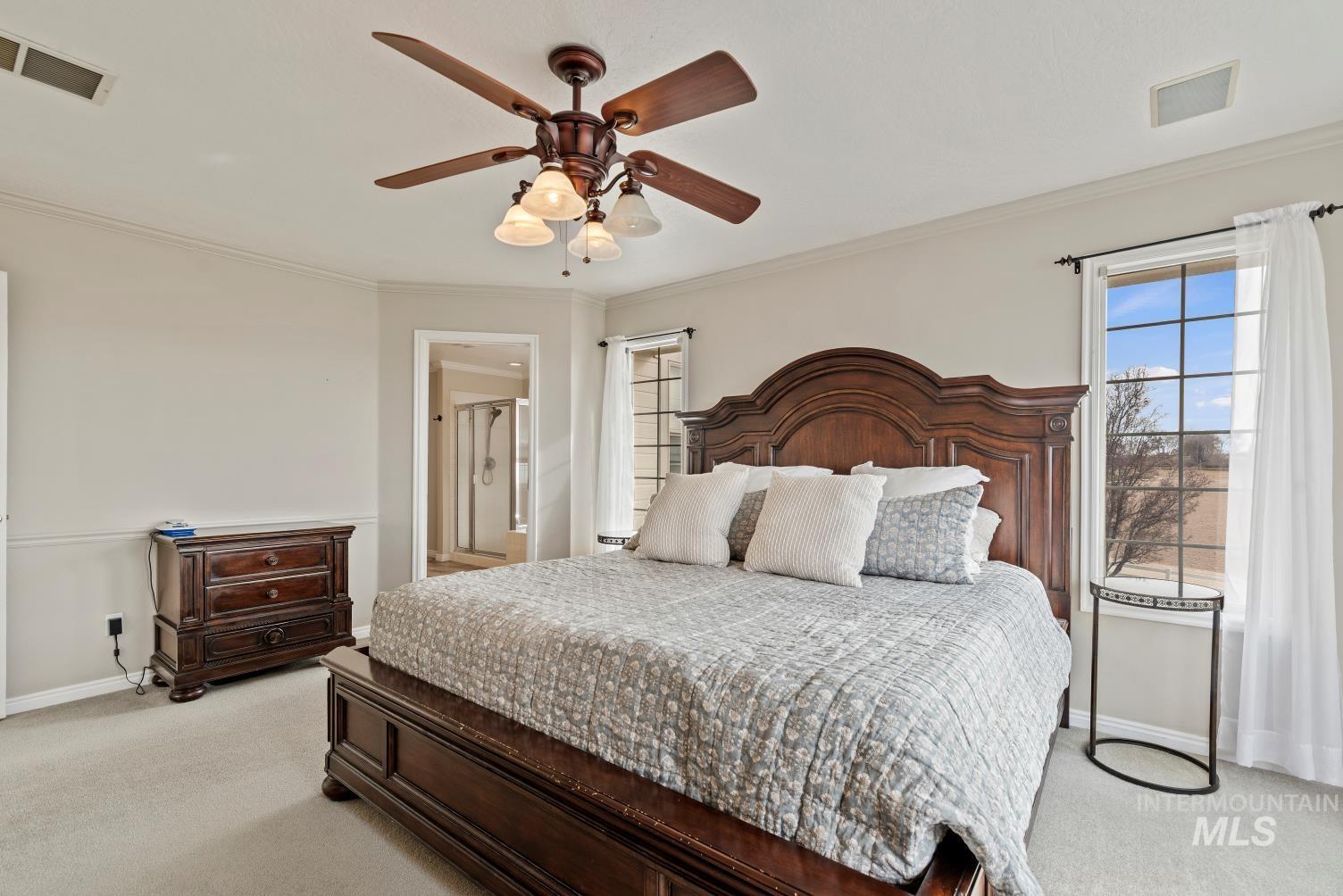 Bedroom featuring light carpet, crown molding, ceiling fan, and ensuite bathroom