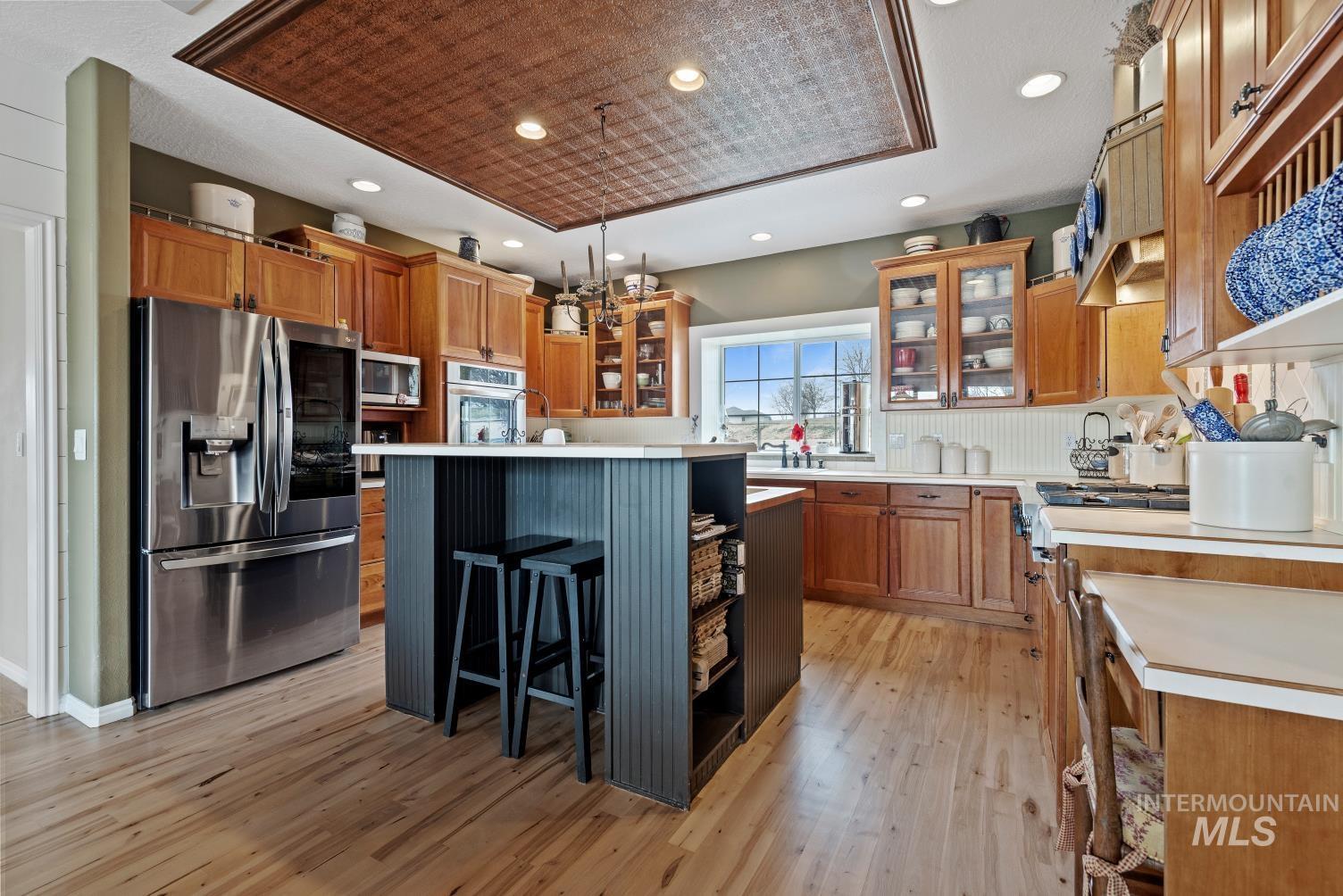 Kitchen featuring glass fronted cabinets, light countertops, stainless steel appliances, a kitchen breakfast bar, and light wood-type flooring