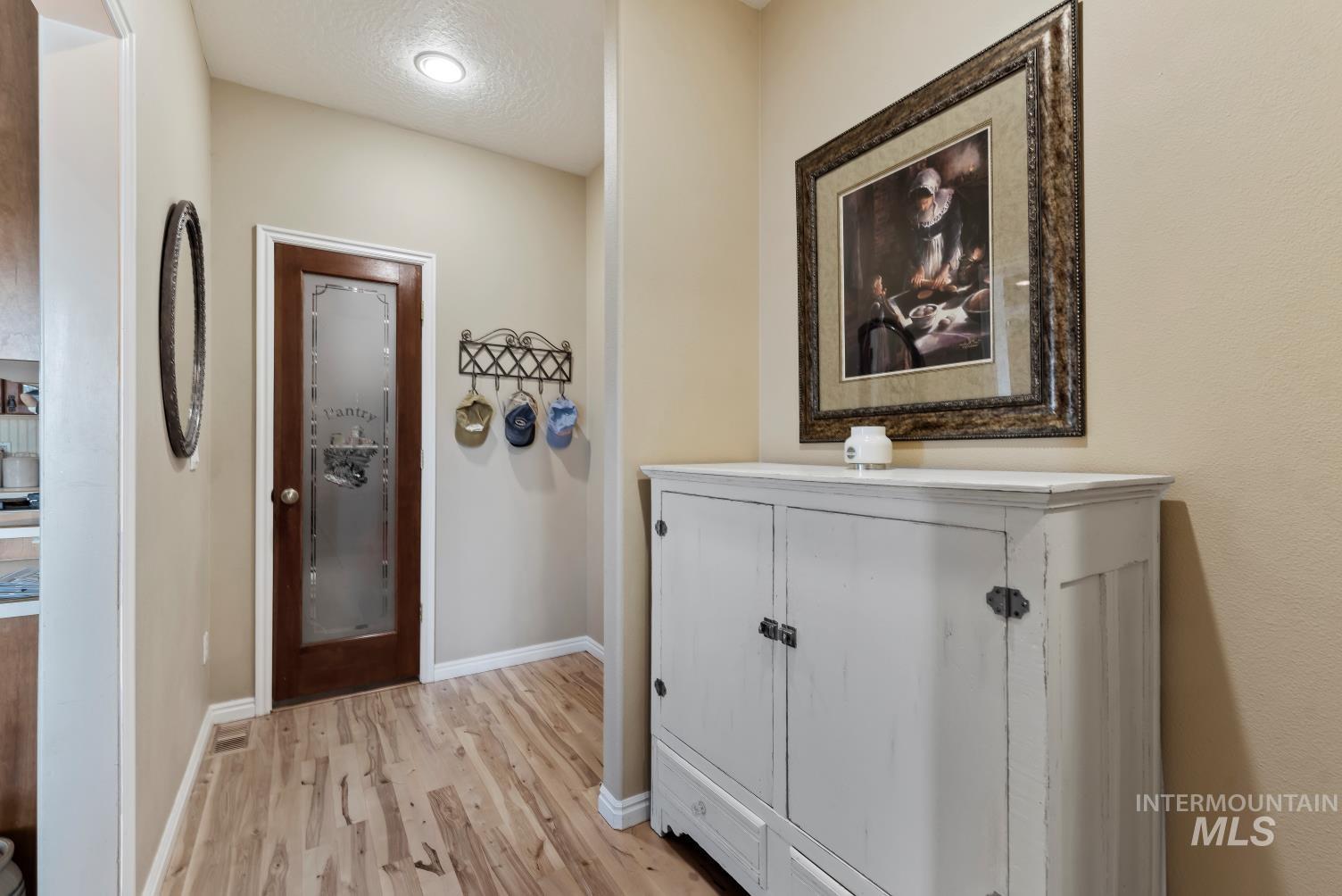 Hall featuring light wood-style flooring and a textured ceiling