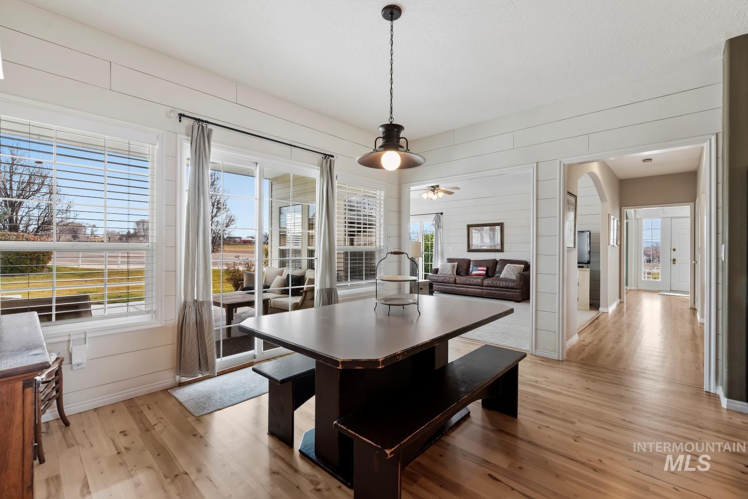 Dining room featuring plenty of natural light, light wood-style floors, wooden walls, ceiling fan, and arched walkways