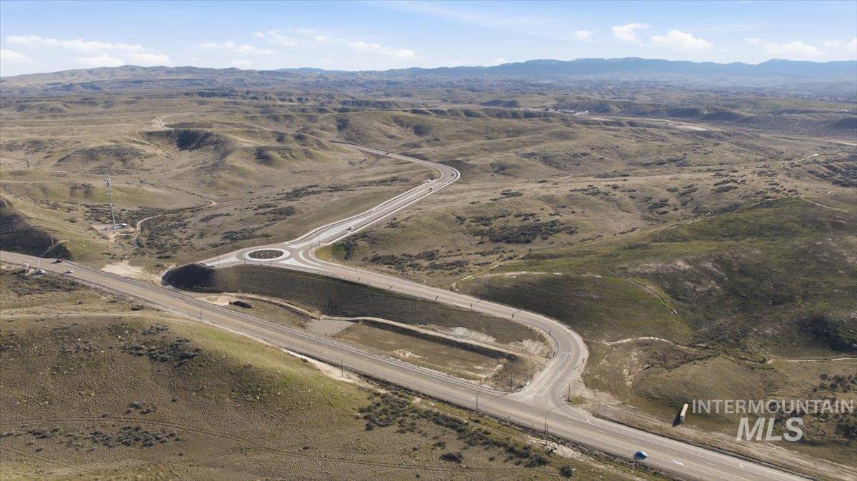 Aerial view of property and surrounding area featuring a mountain backdrop and rural landscape