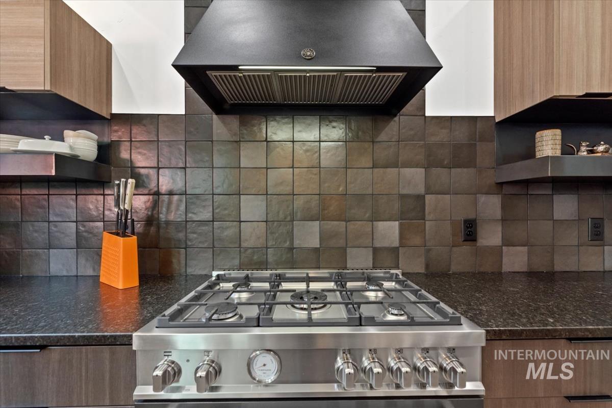 Kitchen featuring extractor fan, modern cabinets, range, and open shelves