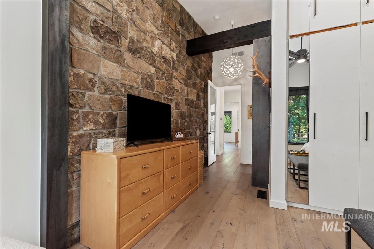 Bedroom with light wood finished floors, beam ceiling, and a high ceiling