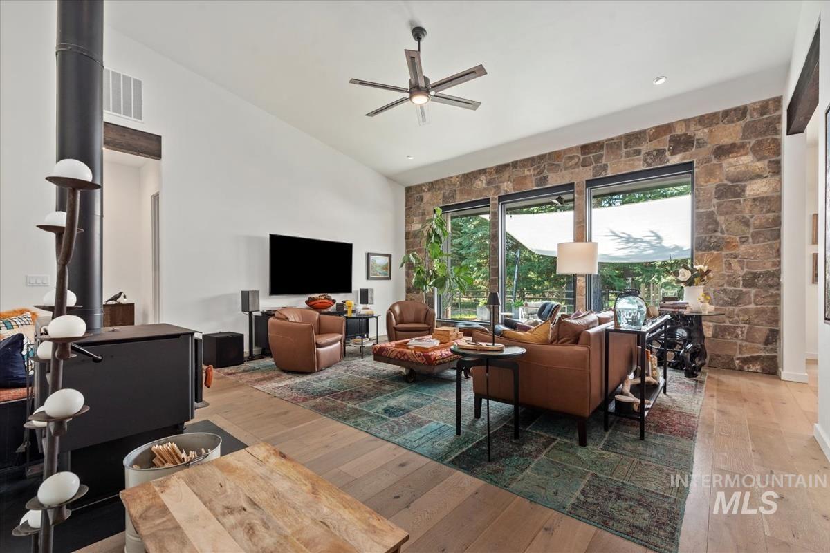 Living area with hardwood / wood-style floors, a ceiling fan, and high vaulted ceiling