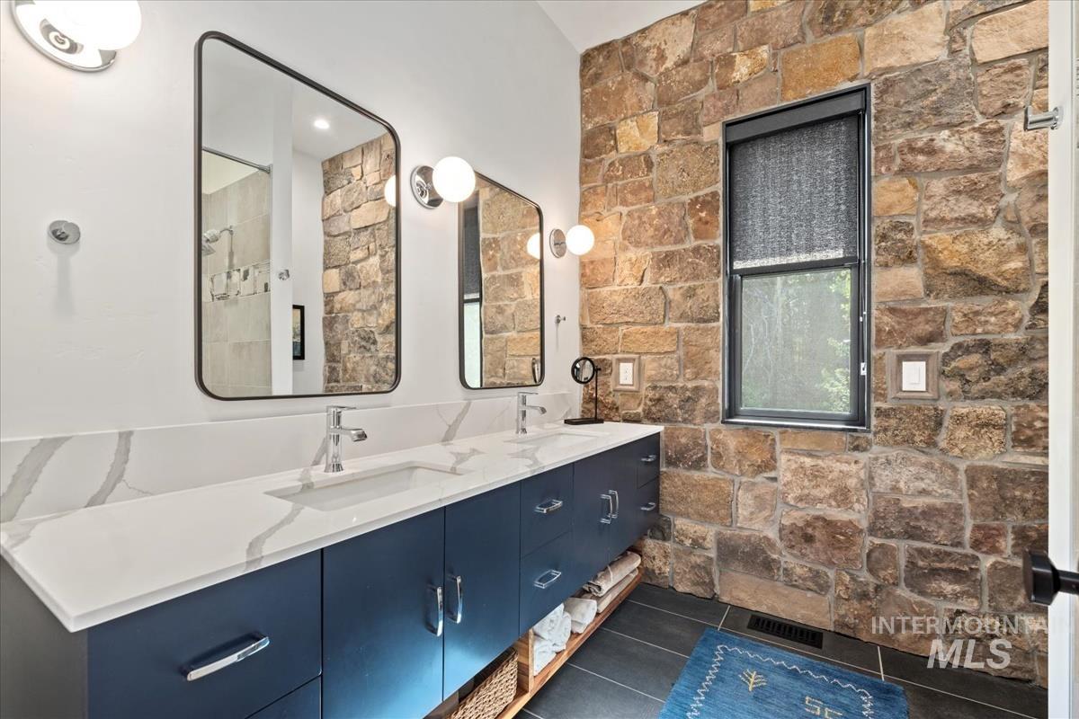 Bathroom featuring double vanity, tile patterned floors, and a shower