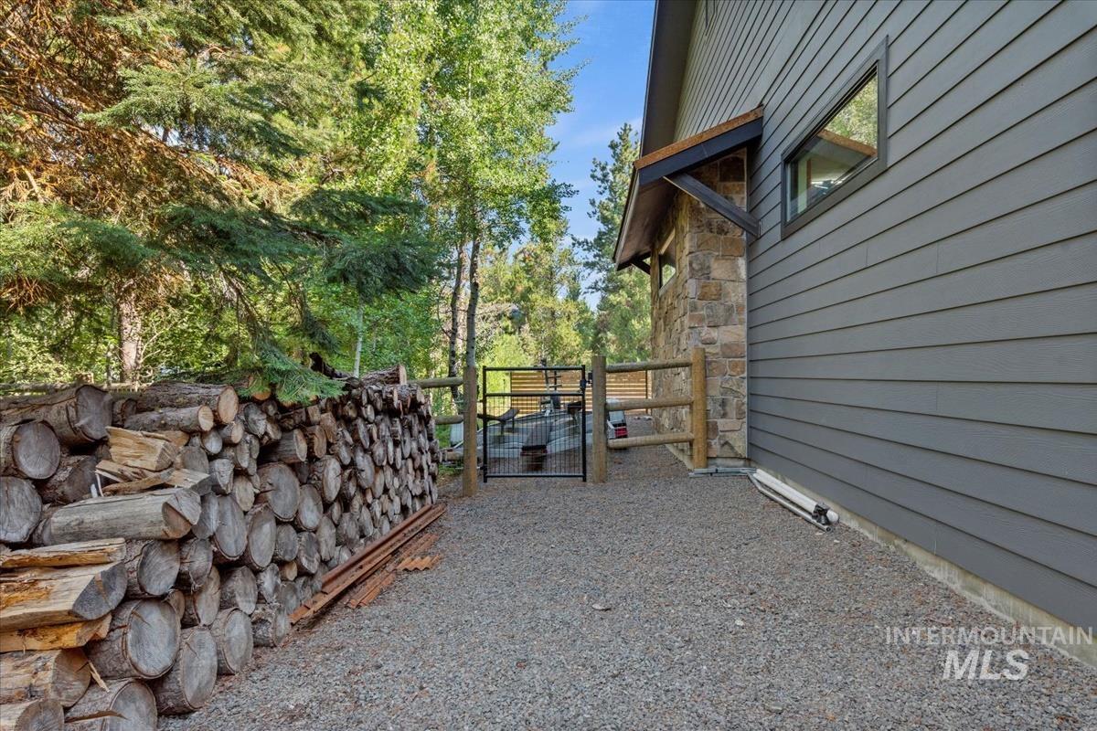 View of side of property with a gate, stone siding, and view of scattered trees