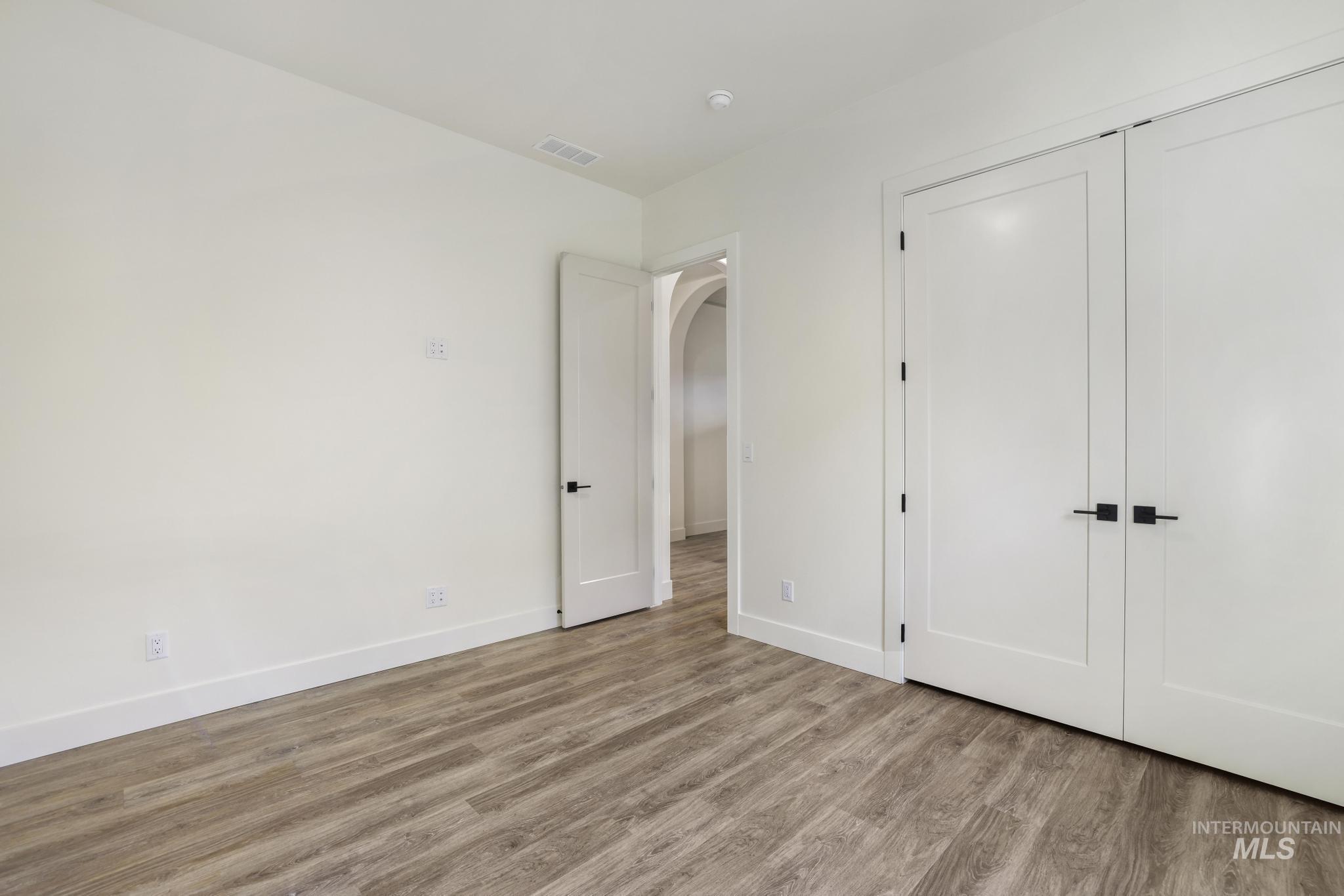 Unfurnished bedroom featuring wood finished floors, arched walkways, and a closet