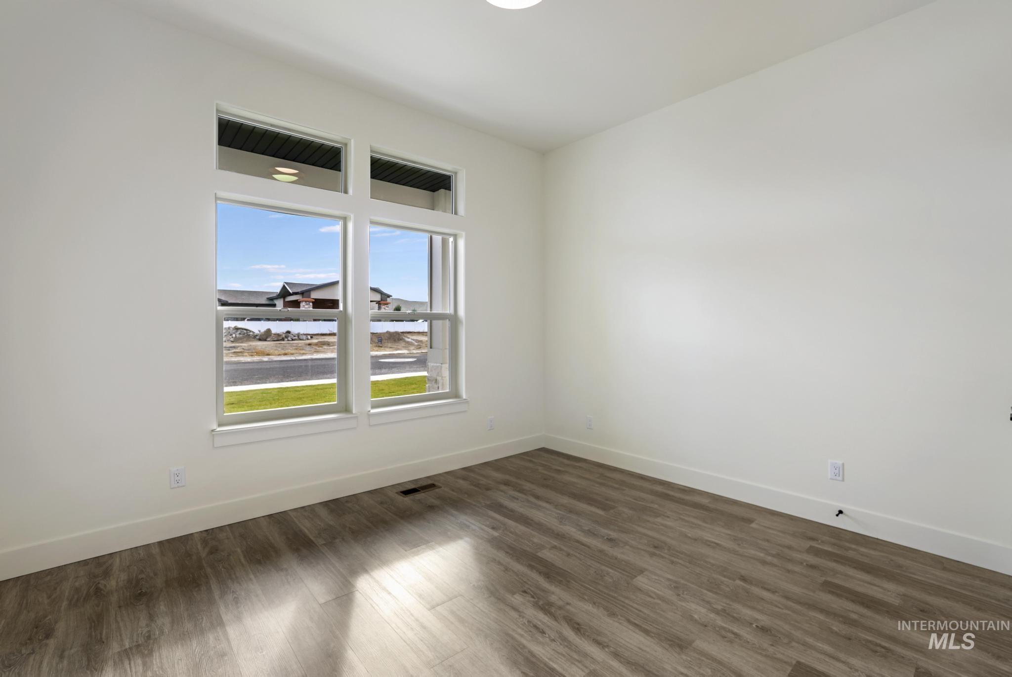 Empty room featuring dark wood-style flooring and baseboards