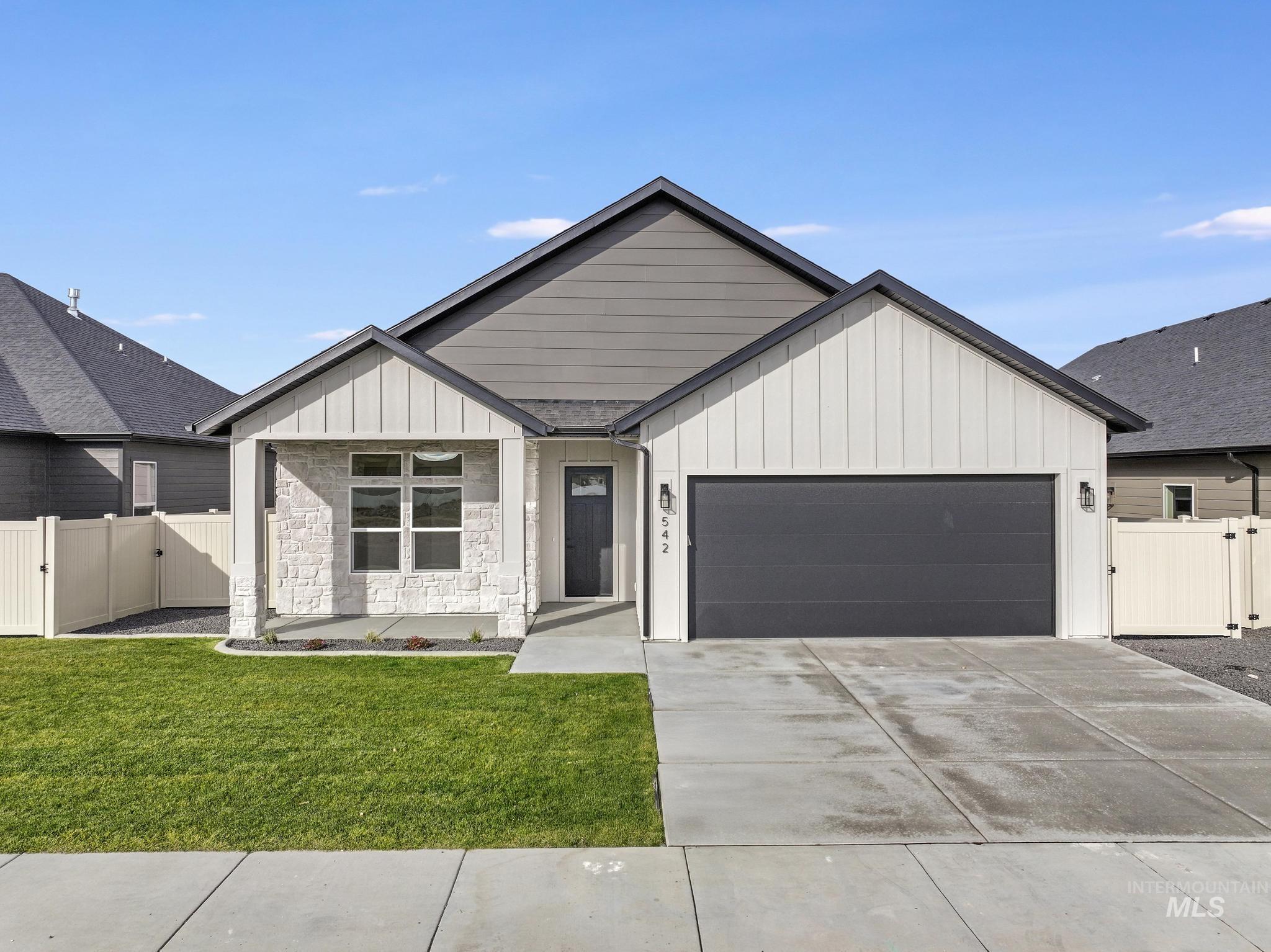 Modern farmhouse featuring a gate, board and batten siding, an attached garage, concrete driveway, and stone siding