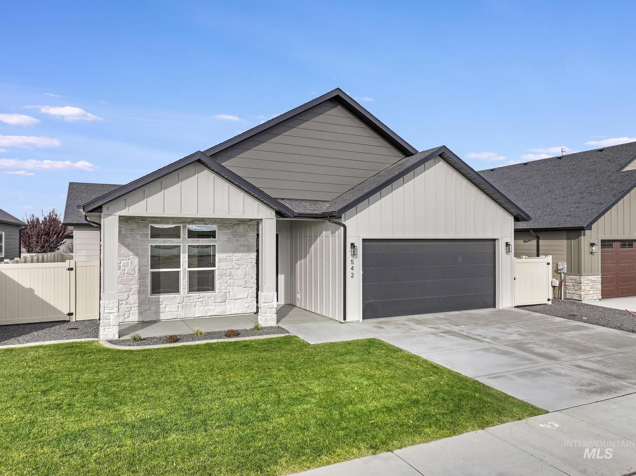 Modern farmhouse featuring stone siding, concrete driveway, board and batten siding, an attached garage, and roof with shingles