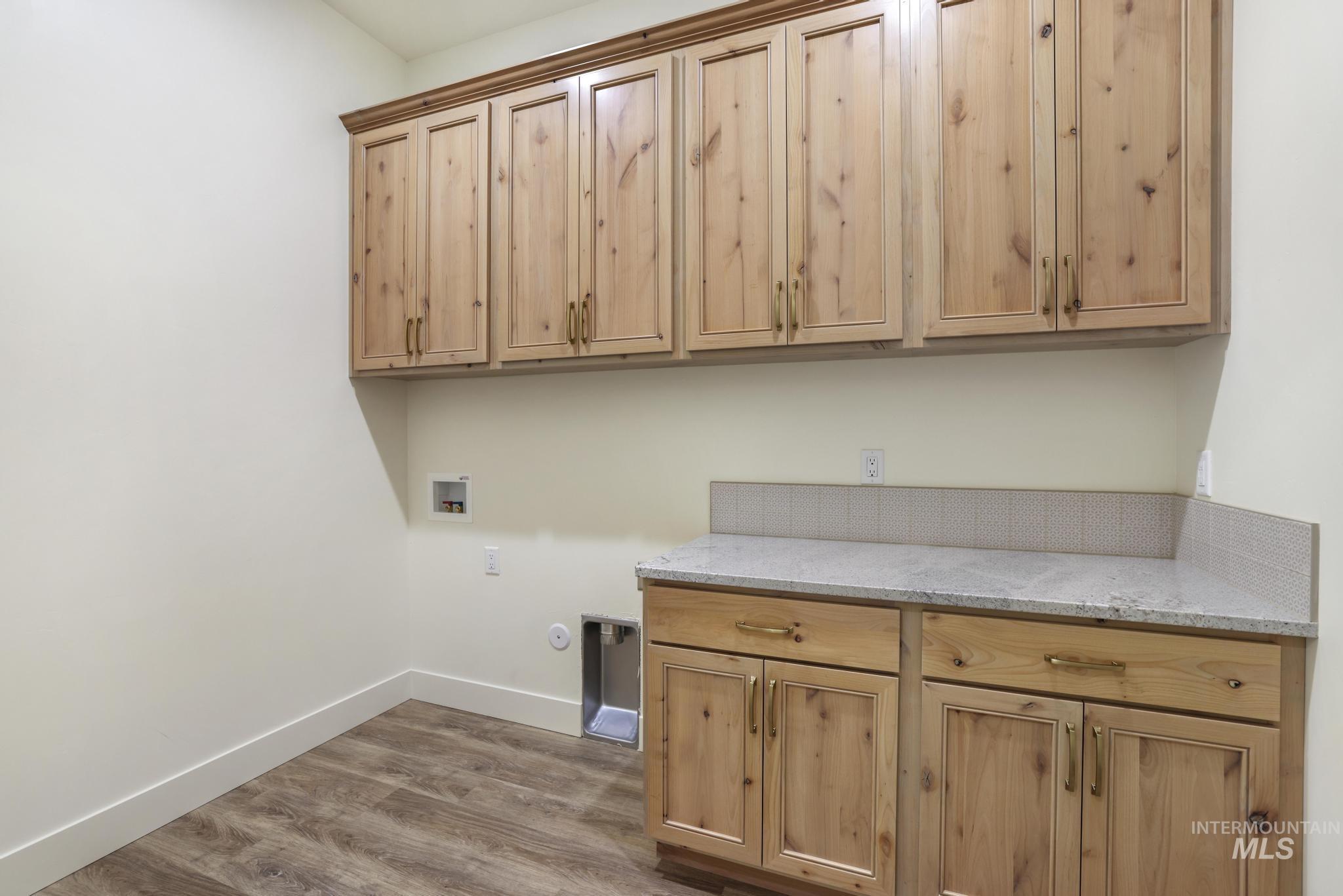 Washroom with hookup for a washing machine, dark wood-style floors, cabinet space, and hookup for a gas dryer