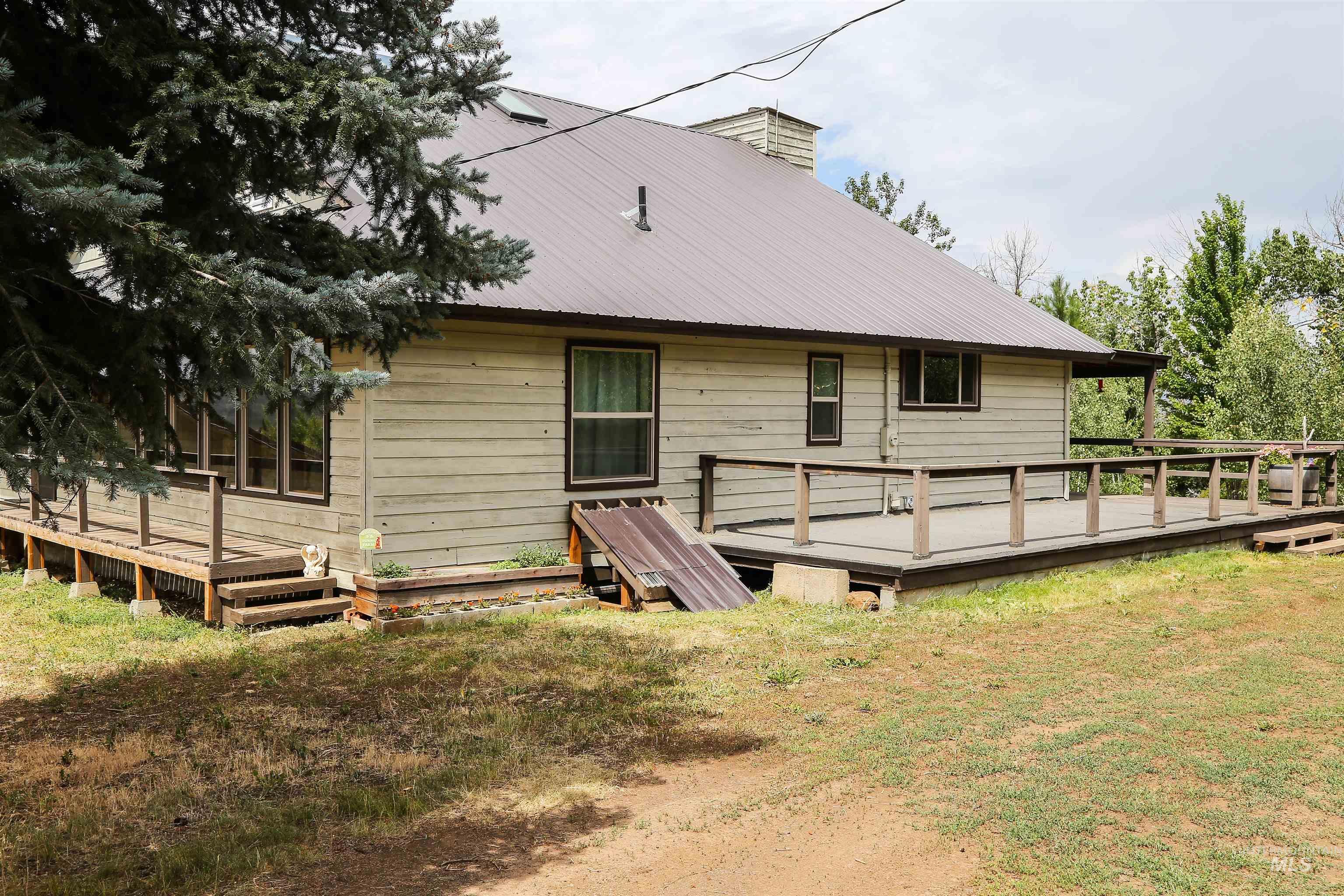 Back of property with a wooden deck, a metal roof, a chimney, and a yard