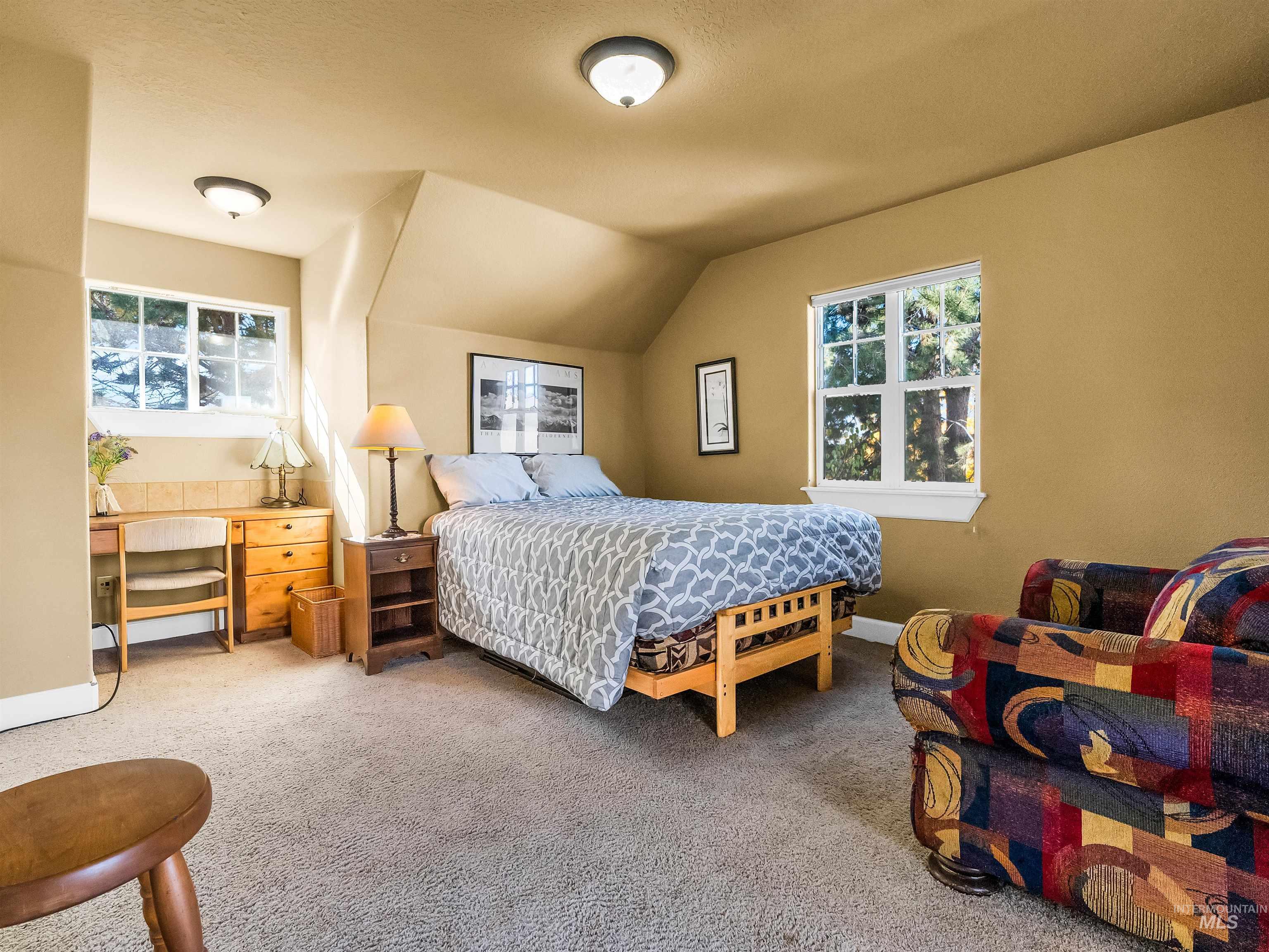 Bedroom with multiple windows, carpet flooring, vaulted ceiling, and an office area