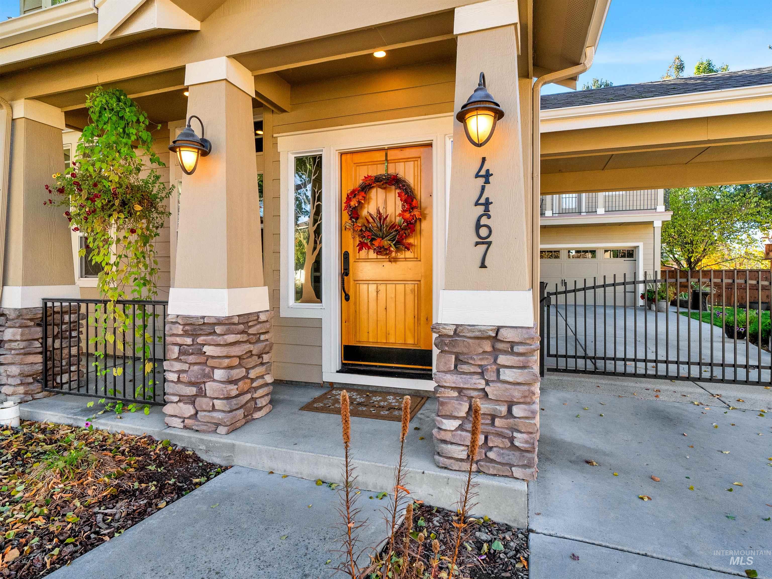 View of exterior entry featuring stone siding, concrete driveway, covered porch, a gate, and a garage