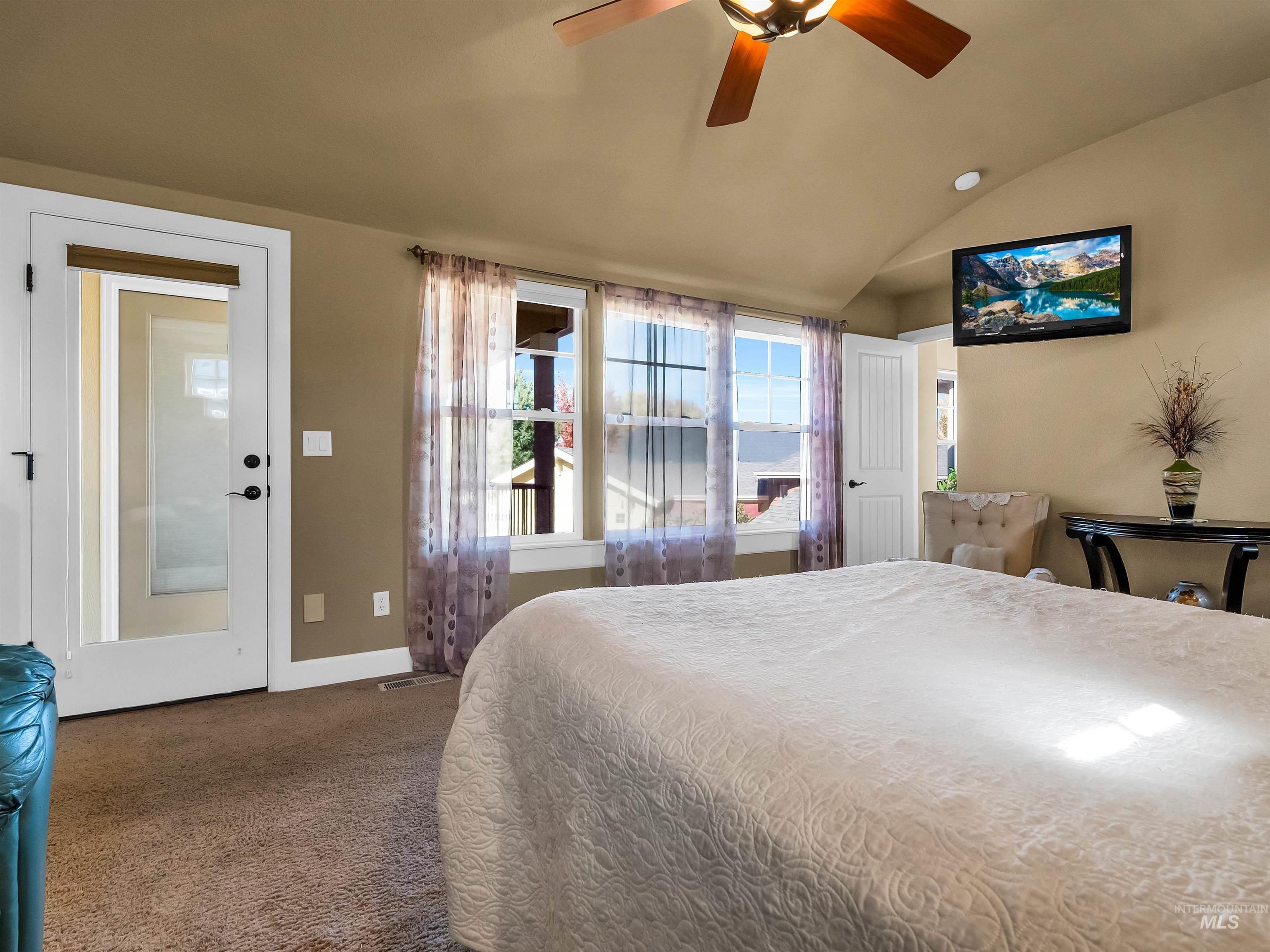 Carpeted bedroom featuring vaulted ceiling and ceiling fan