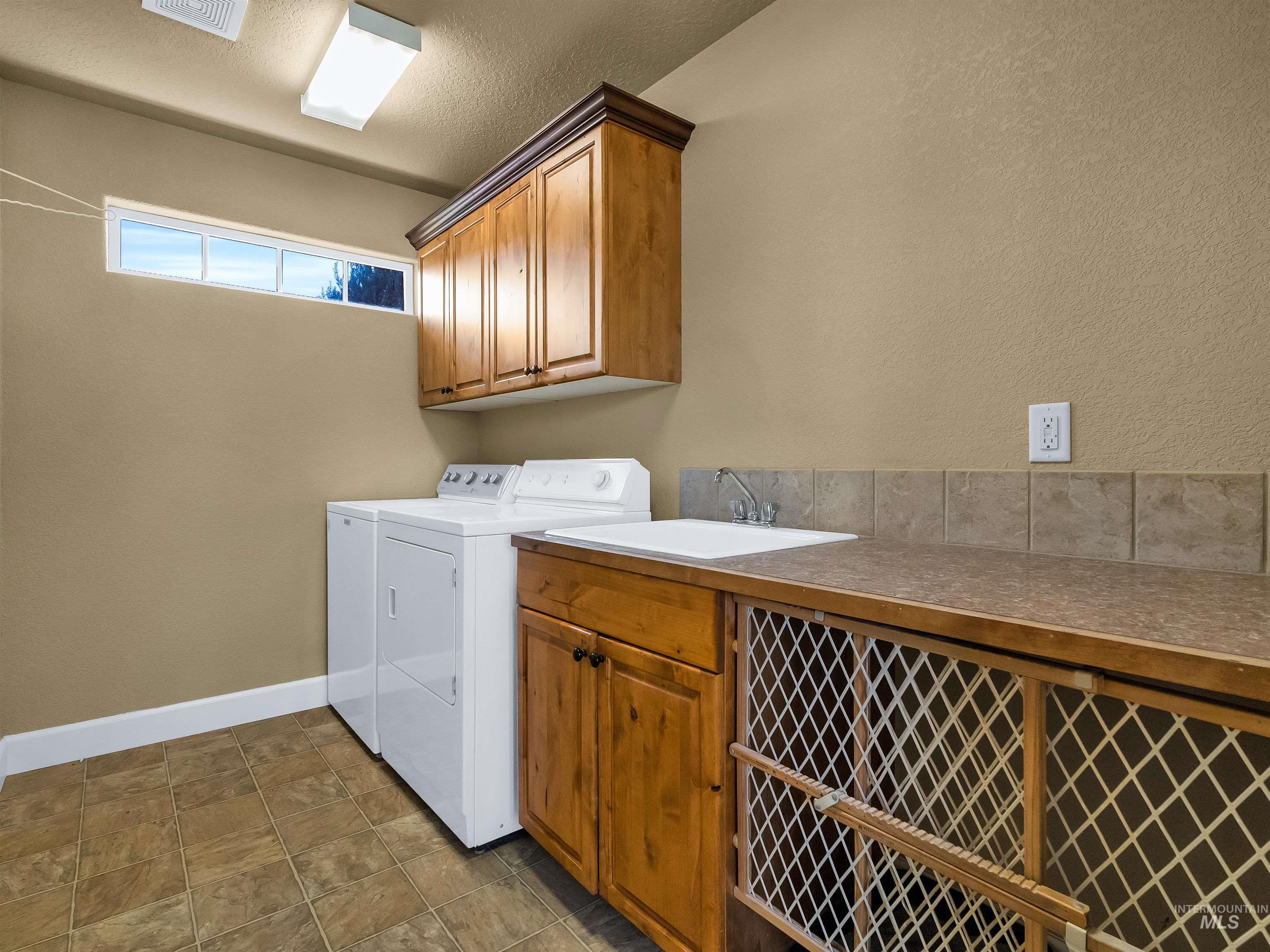 Laundry area with separate washer and dryer, cabinet space, a textured ceiling, and a textured wall