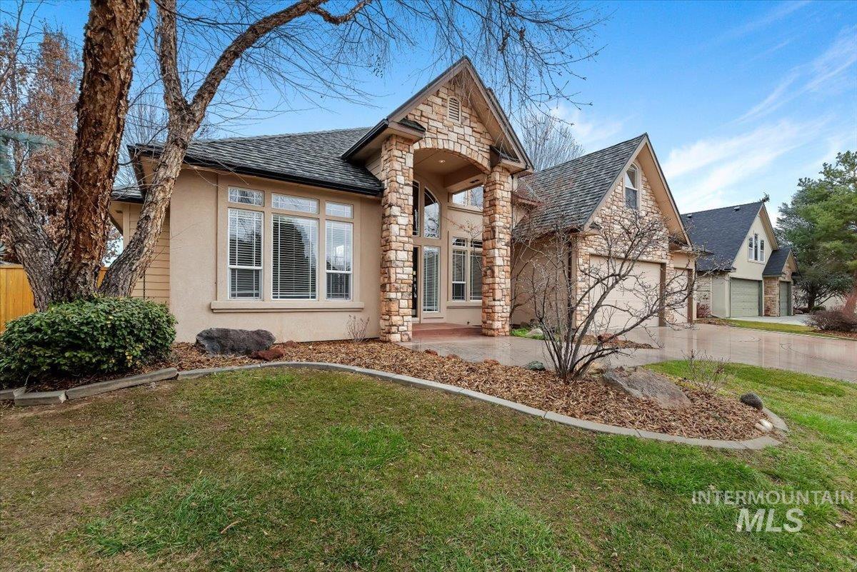View of front of home with stone siding, concrete driveway, an attached garage, a front yard, and stucco siding