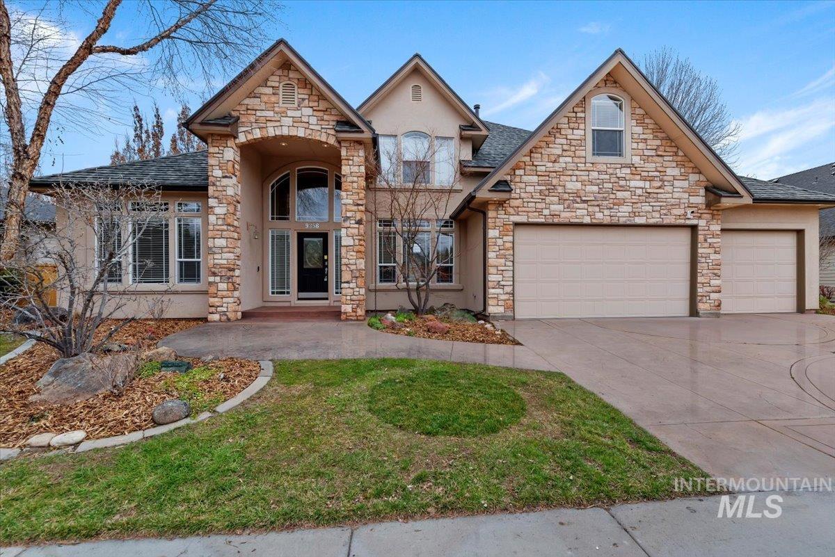 View of front of house featuring concrete driveway, stone siding, a garage, and a shingled roof