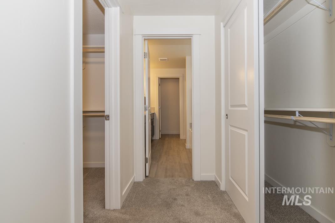Hall with light colored carpet and baseboards
