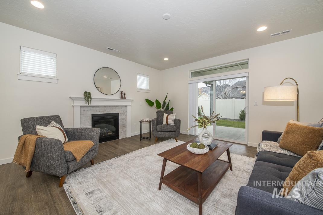 Living area with a brick fireplace, healthy amount of natural light, wood finished floors, and recessed lighting