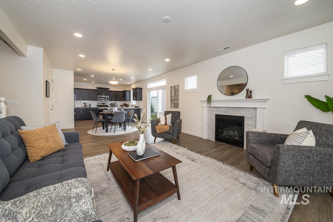 Living room featuring recessed lighting, a fireplace, light wood finished floors, and a textured ceiling