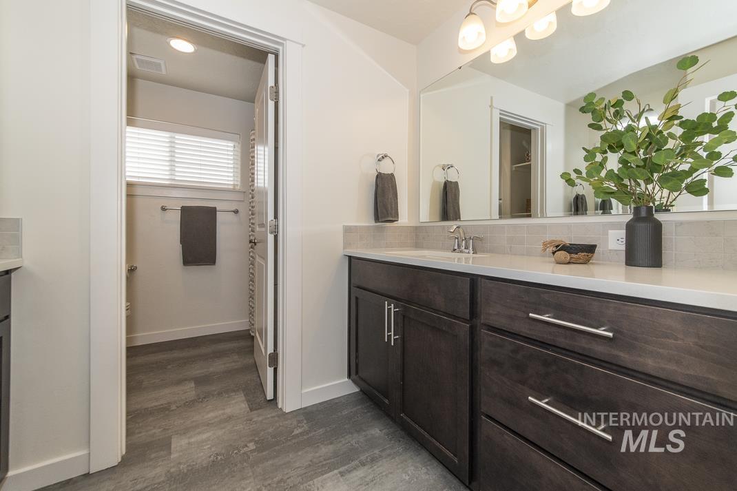 Bathroom with vanity, backsplash, and dark wood finished floors