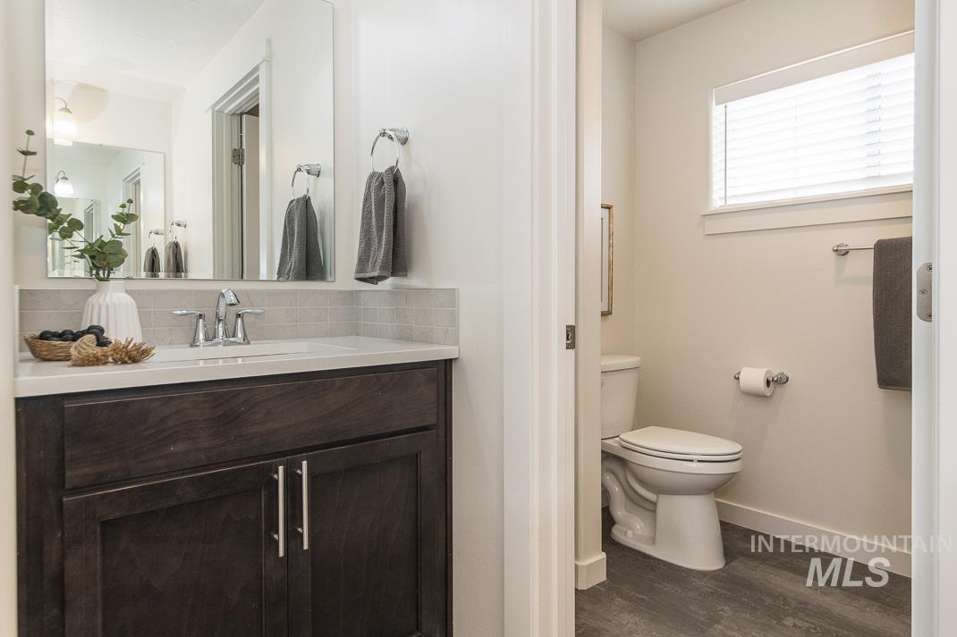 Bathroom featuring vanity, backsplash, and dark wood-style flooring