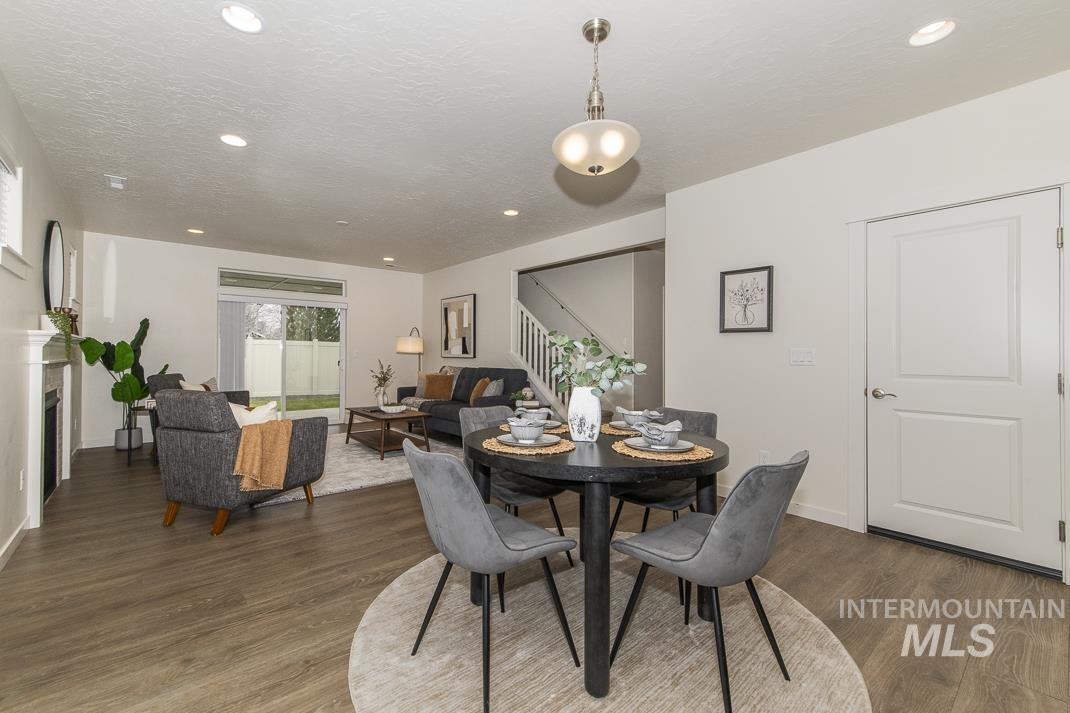 Dining area featuring a fireplace, stairway, wood finished floors, recessed lighting, and a textured ceiling