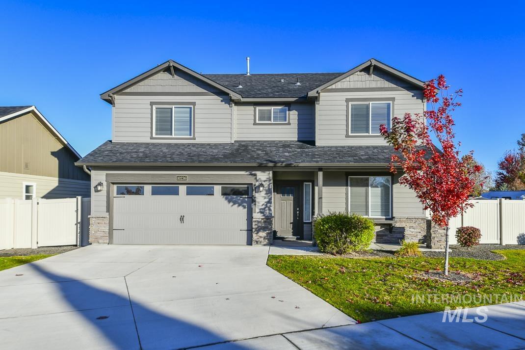 Craftsman-style house featuring stone siding, a shingled roof, concrete driveway, and an attached garage
