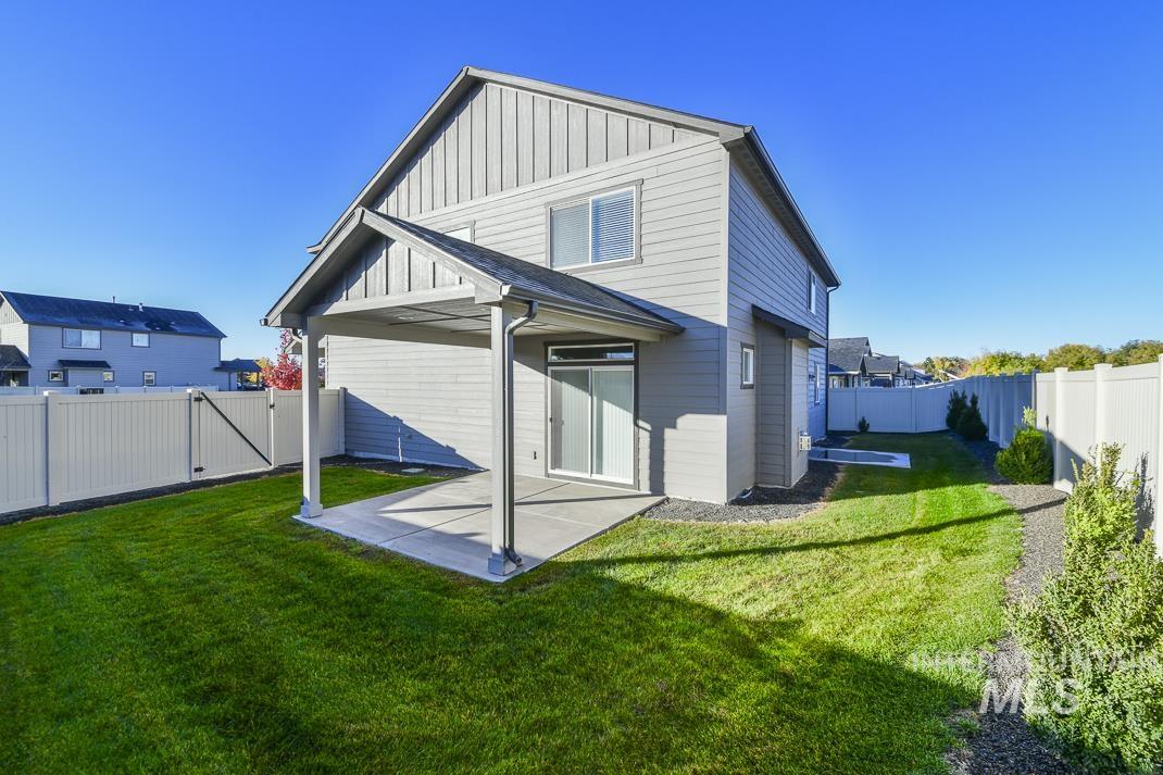 Back of property featuring board and batten siding, a fenced backyard, a patio area, and a gate
