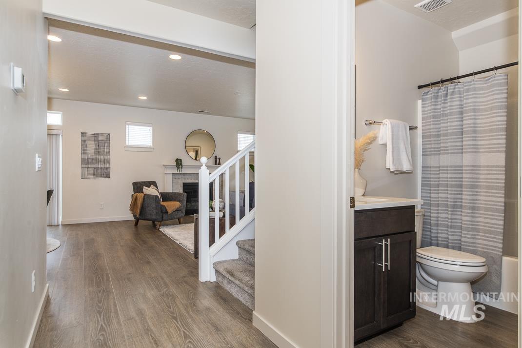 Bathroom with vanity, dark wood finished floors, a fireplace, recessed lighting, and shower / bathtub combination with curtain