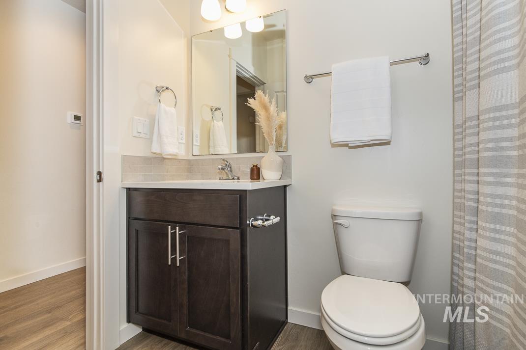 Full bathroom with vanity, curtained shower, and wood finished floors